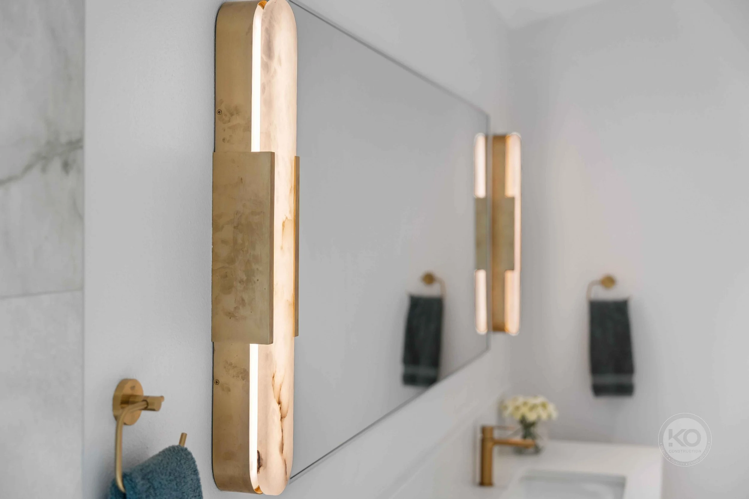 Custom vanity with illuminated mirror and brass fixtures in a Lake Tapps primary bathroom remodel.