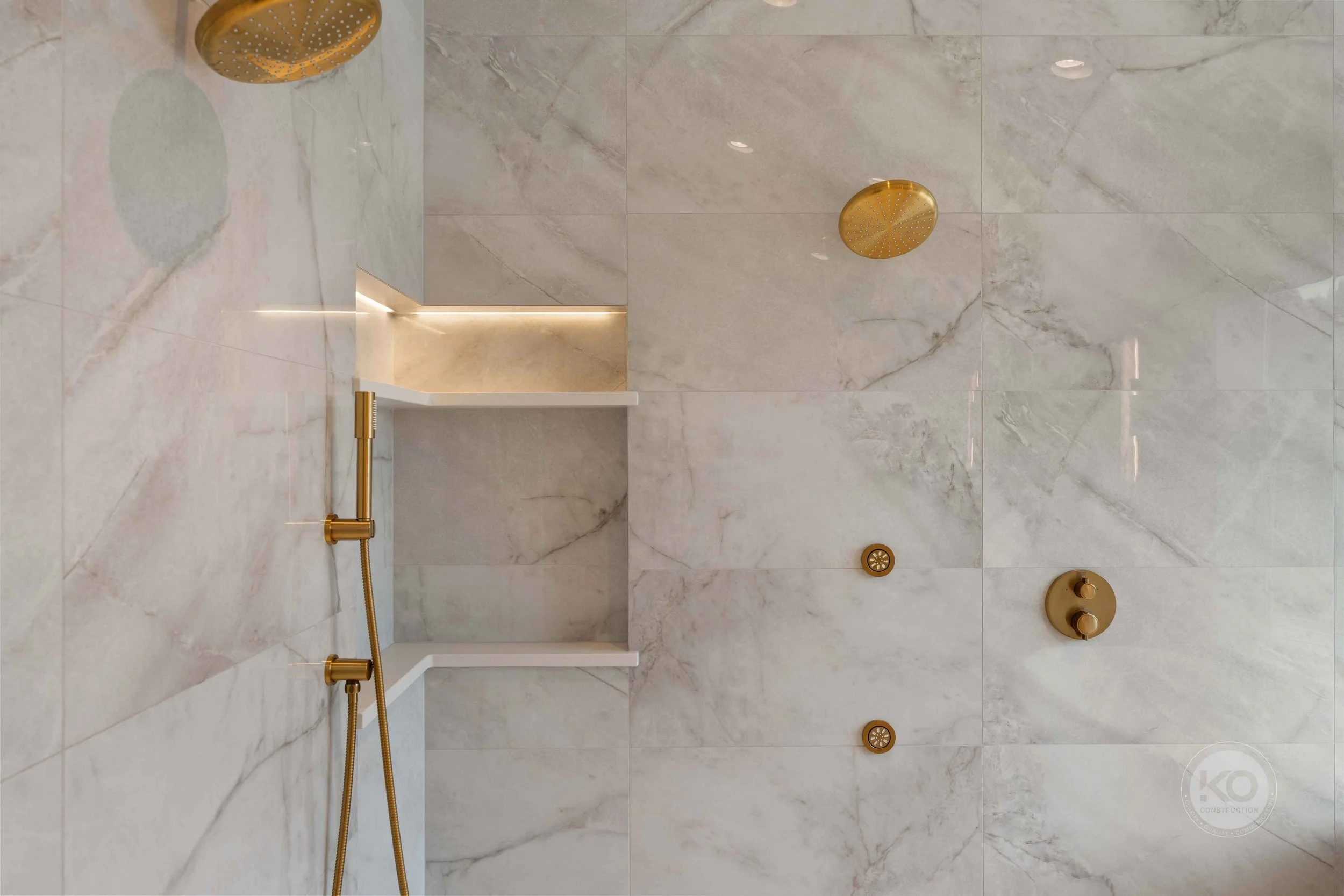 Luxury walk-in shower with brass fixtures and large-format tile in a Lake Tapps bathroom remodel.