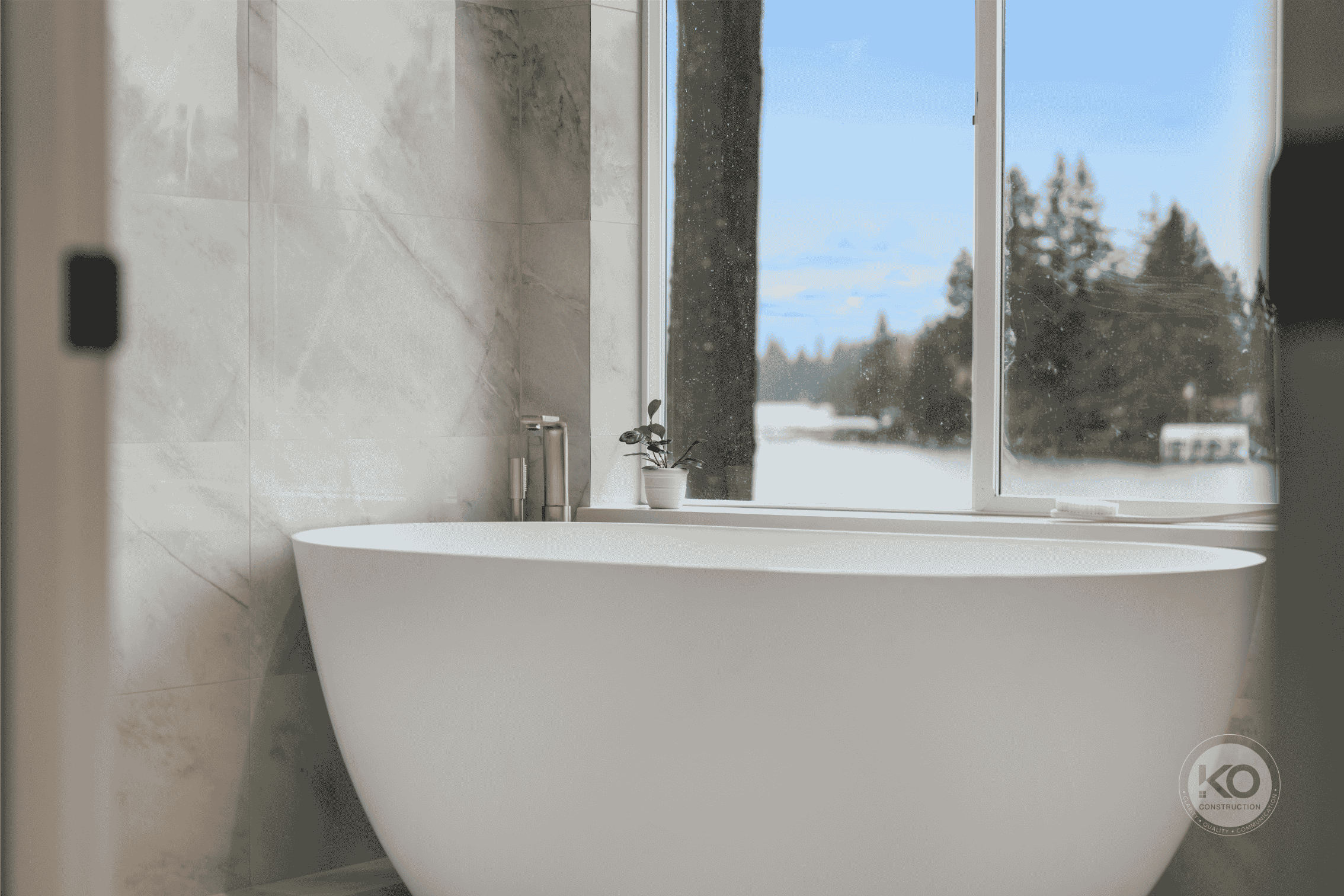 Freestanding soaking tub overlooking Lake Tapps in a luxury primary bathroom remodel.