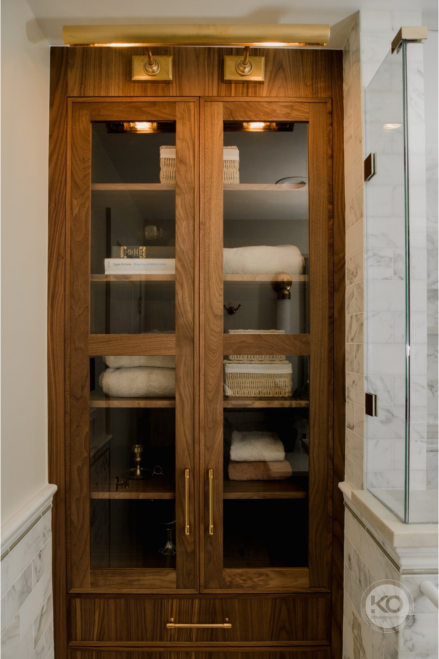 Custom walnut linen cabinet providing built-in storage in a Federal Way primary bathroom remodel.