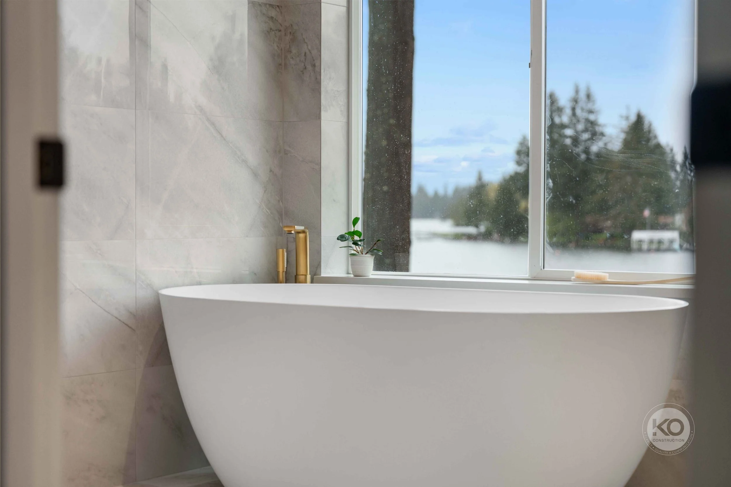 Freestanding soaking tub overlooking Lake Tapps in a luxury primary bathroom remodel.