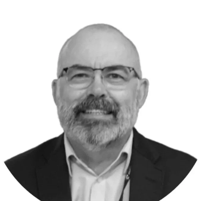 Black and white portrait of a smiling middle-aged man with glasses, a beard, and a mustache, wearing a suit jacket and shirt.