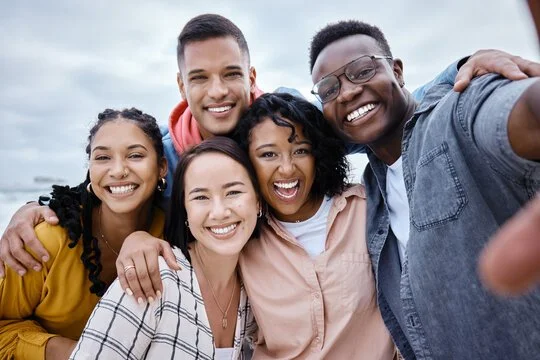 Group of five people taking selfie and smiling