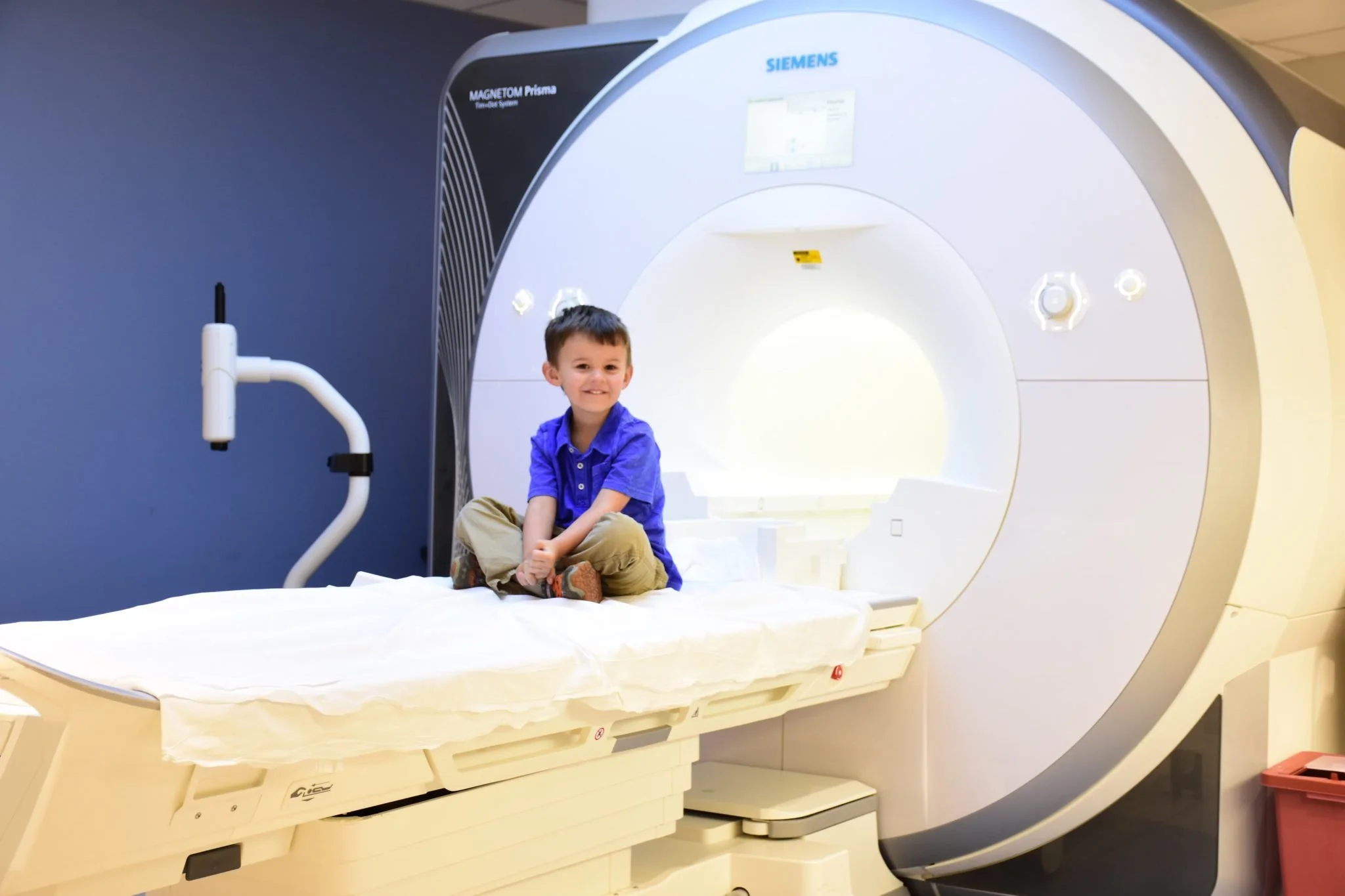 Young child sitting on the table of an MRI scanner