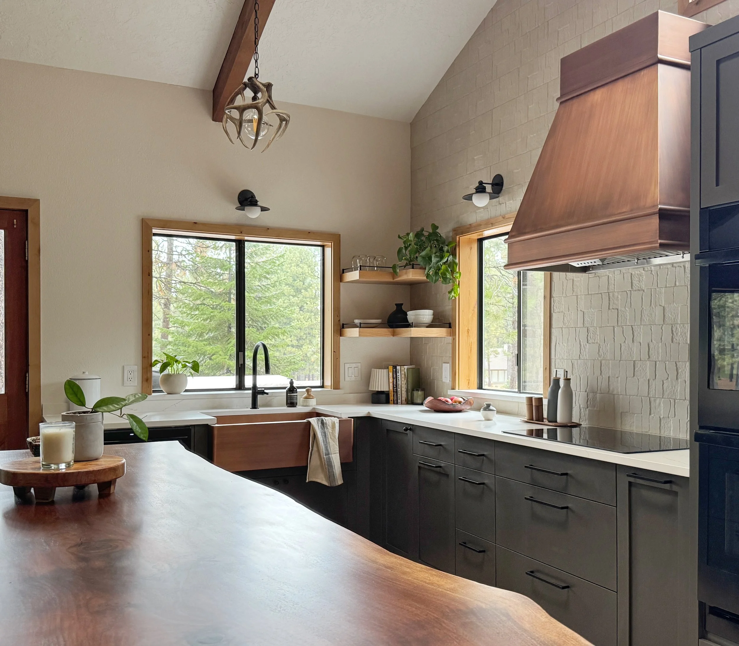 Live-Edge Walnut Countertop Slab, dark kitchen cabinets, stone-look backsplash and a copper range hood elevates this Black Butte Ranch kitchen remodel