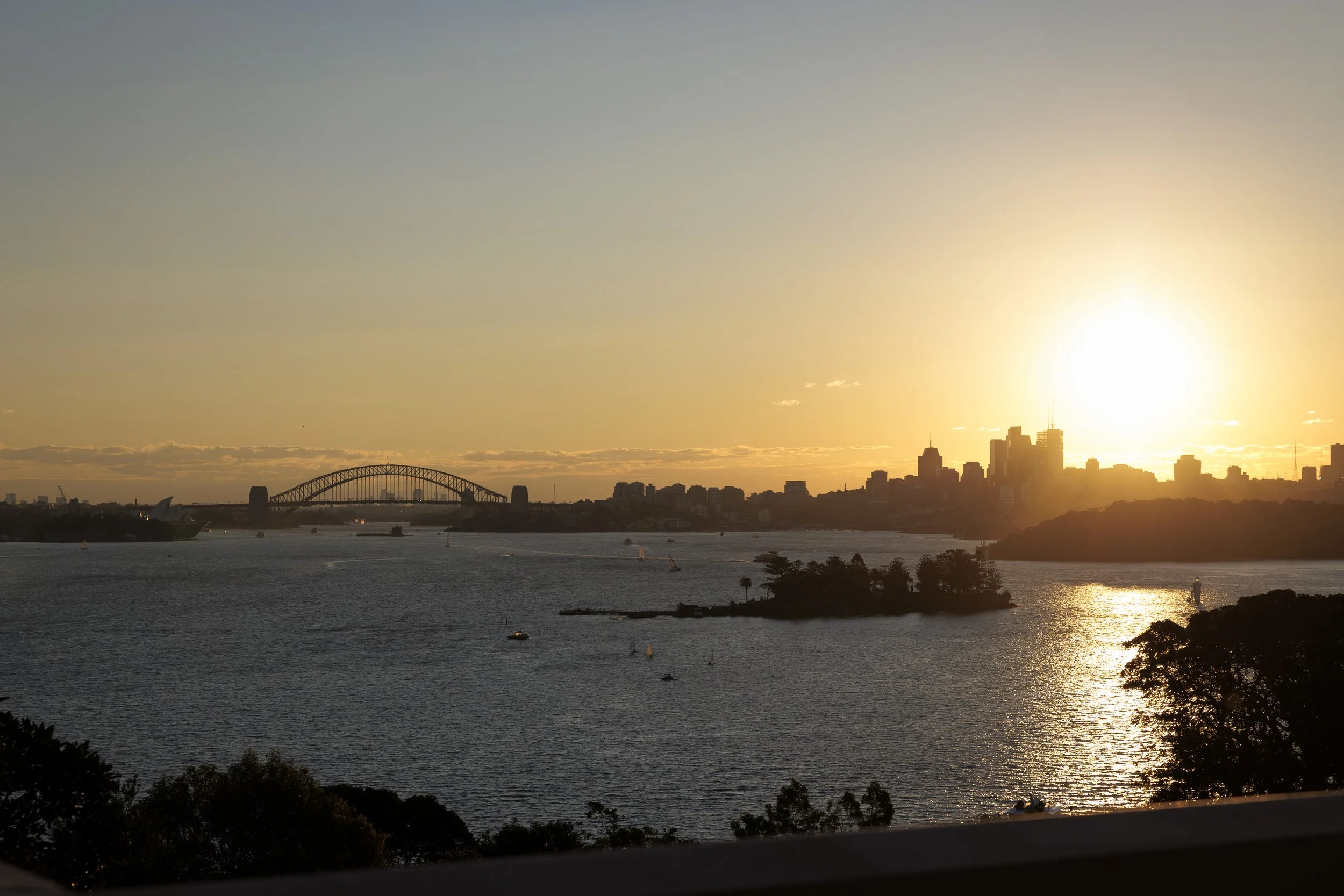 Sunset over Sydney Harbour with the Sydney Opera House and Harbour Bridge silhouette.