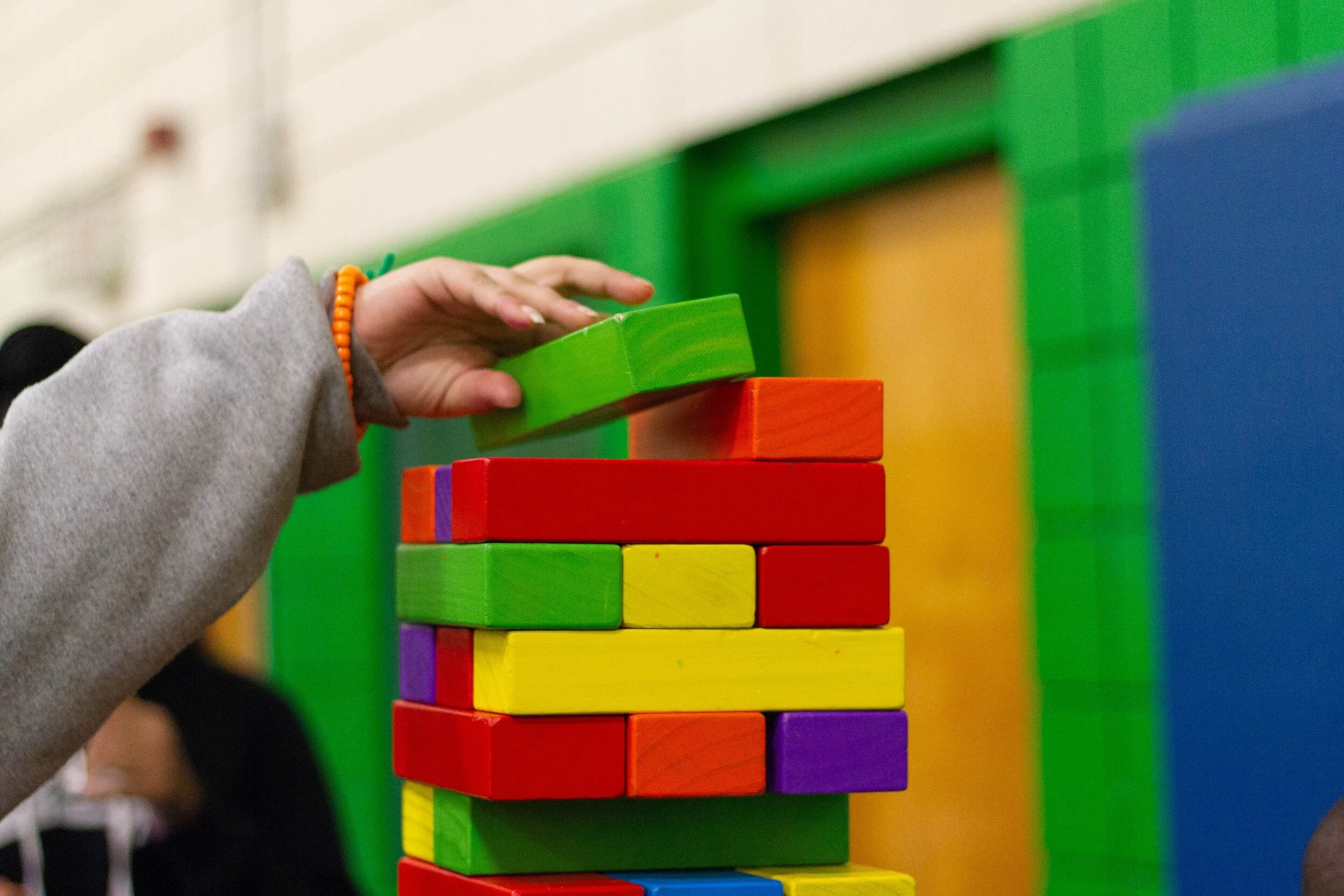 Un enfant dépose un bloc de bois sur une tour de bloc