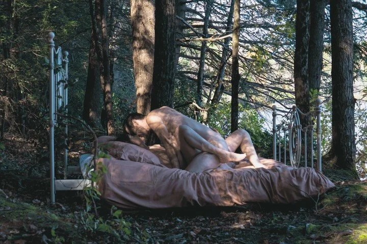 At dawn, fishermen drifting across the still pond catch a ripple of motion in the woods&mdash;two lovers wrapped in one another like entwined trees, their limbs woven with the earth. Sunlight and shadow play upon their skin, painting them in shifting