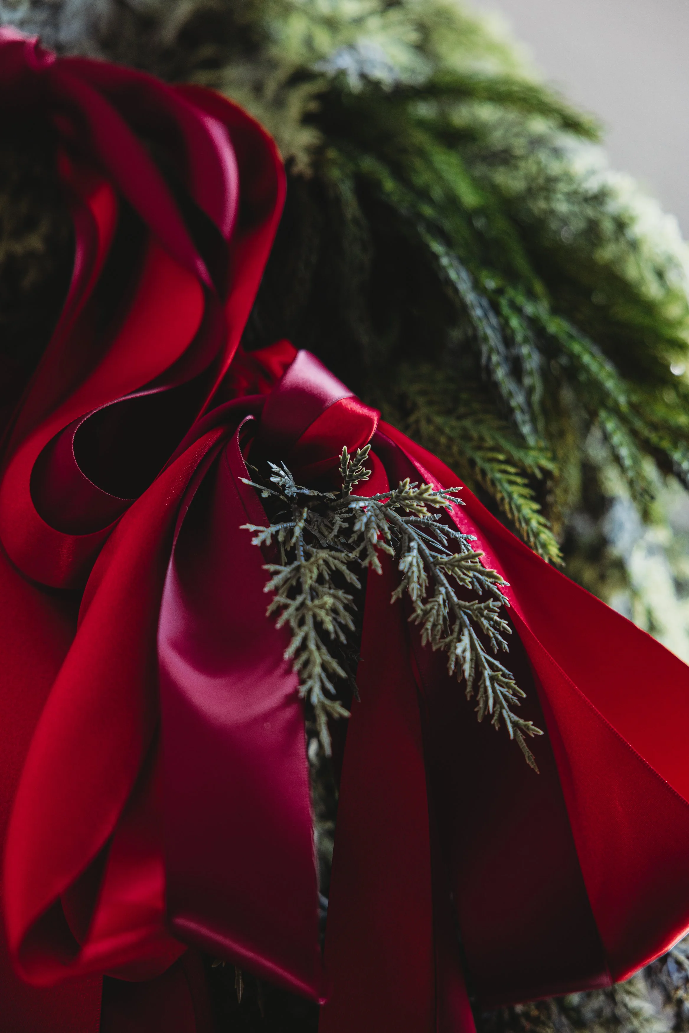 Close-up of red satin fabric with some greenery, possibly a floral arrangement or decorative piece.