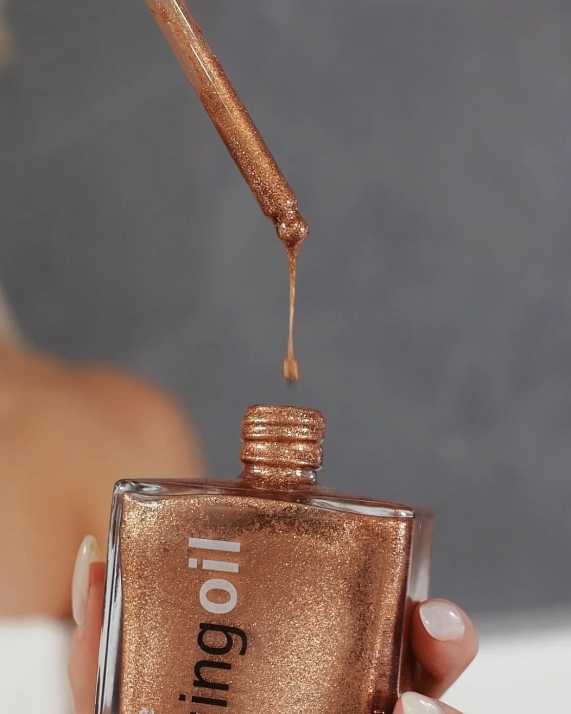 Shimmer bronzing oil dripping from dropper showcasing rich golden texture