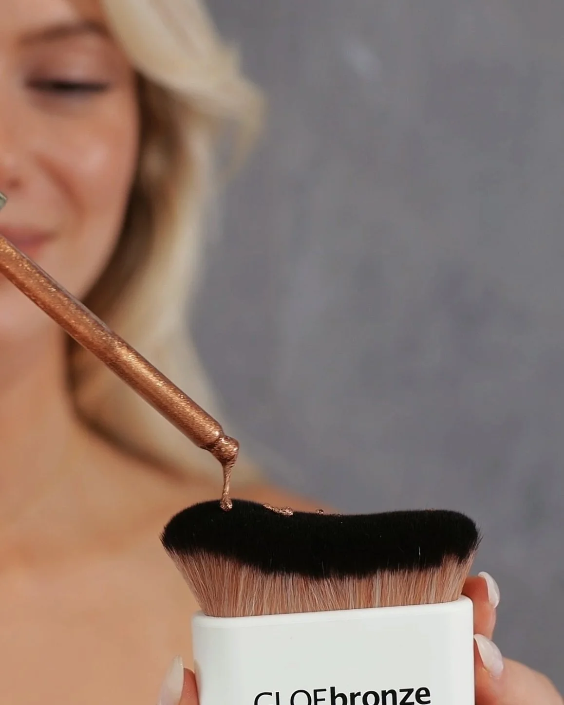 Vegan bronzing oil being applied to kabuki brush for easy body blending