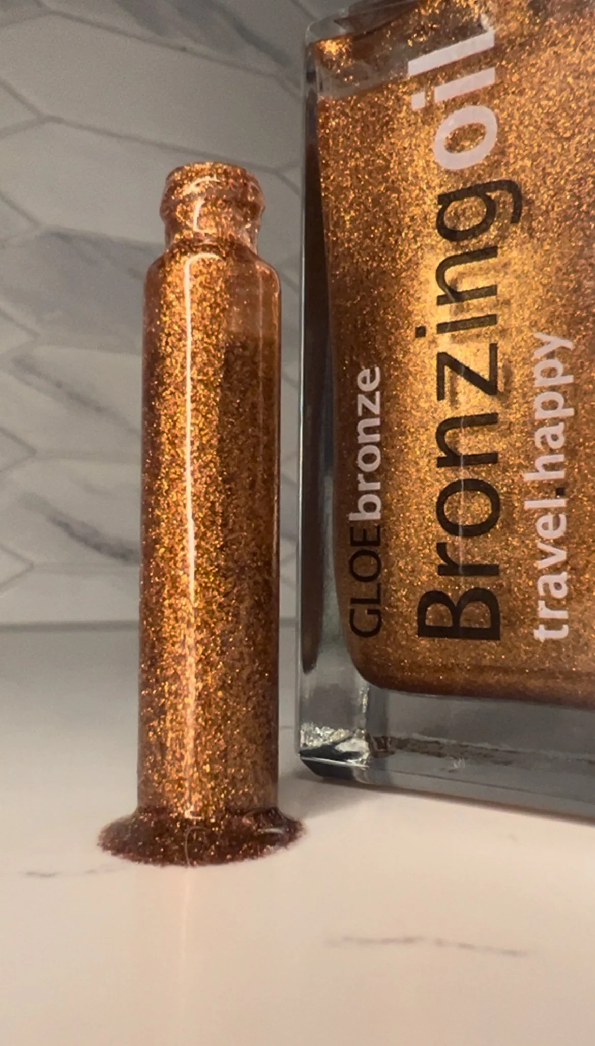 GLOEbronze bronzing oil full size and mini travel bottle on white marble background