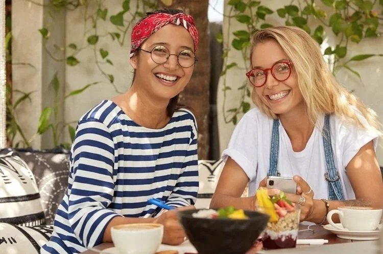 Twee jonge vrouwen met bril aan de koffie