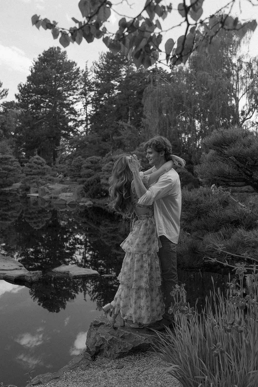 a couple hugging by a pond at the Botanic Garden in Denver