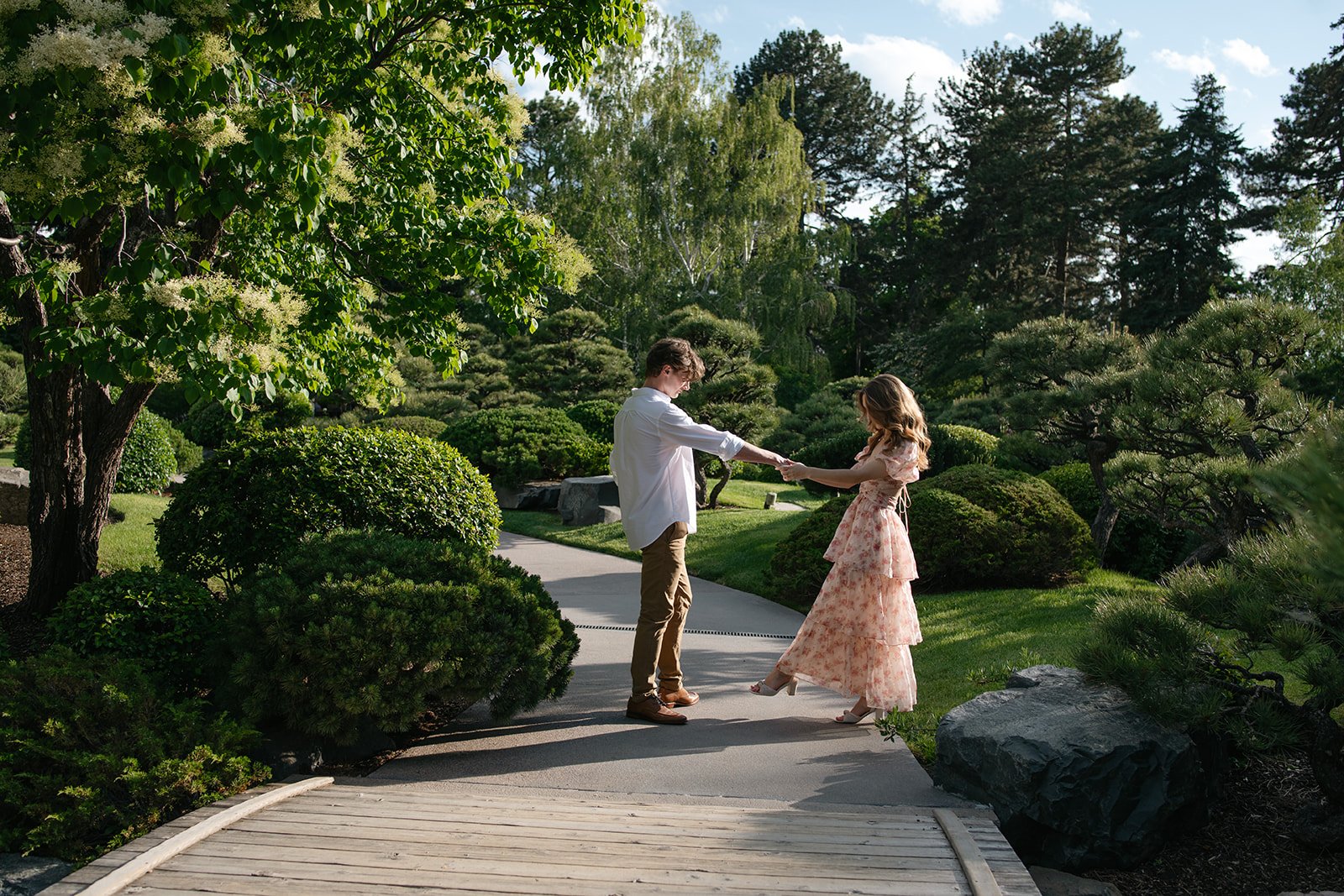 a newly engaged couple dancing on a path at a garden, taken by a Denver engagement photographer