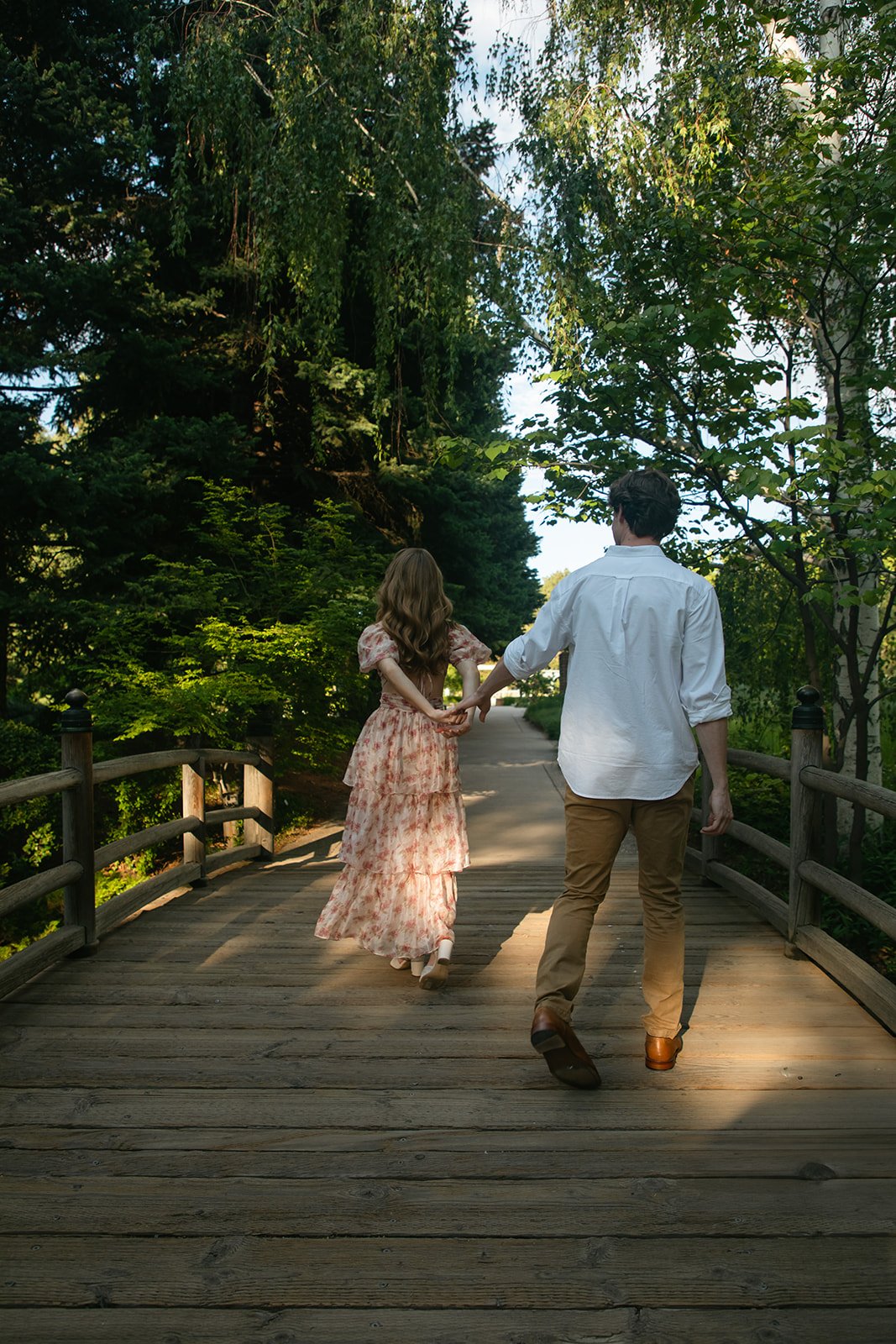a woman leading a man down a bridge during their Denver engagement photos