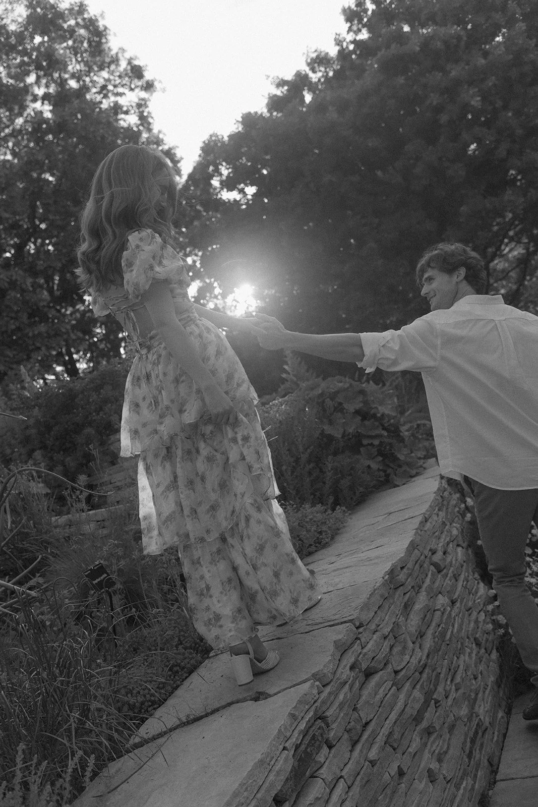 a woman walking on a ledge and a man holding her hand as she does
