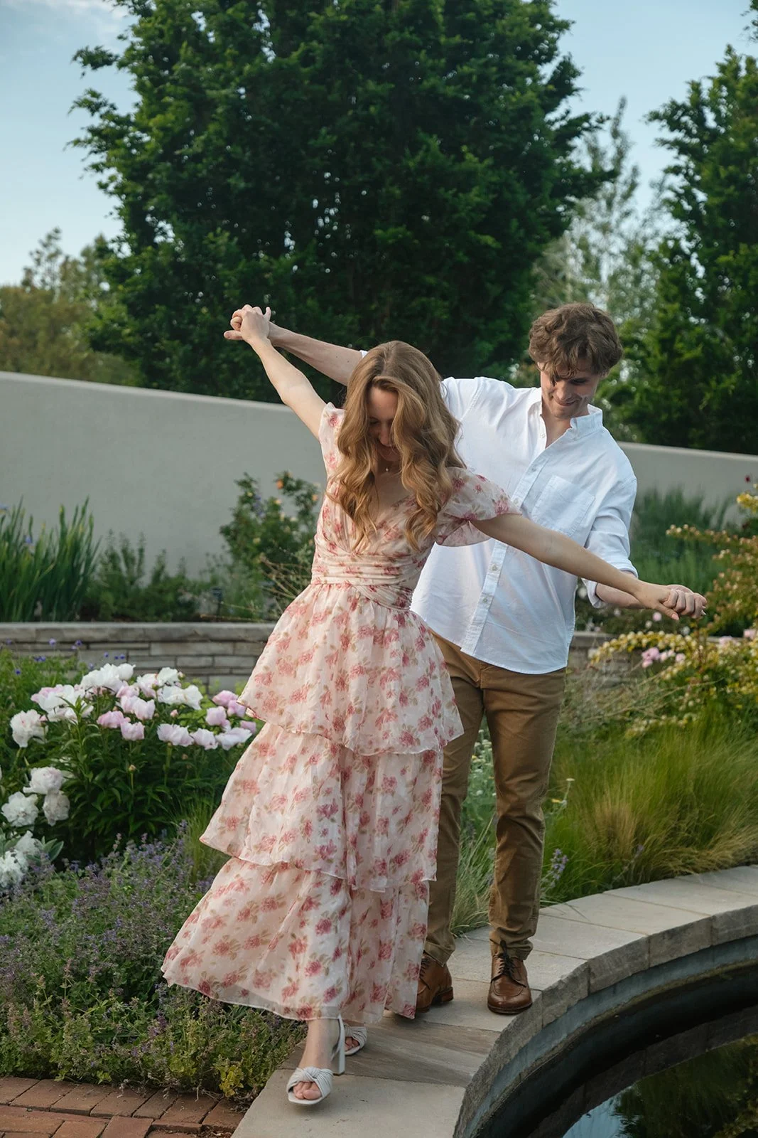 a couple walking on the ledge of a fountain together, taken by a Denver engagement photographer