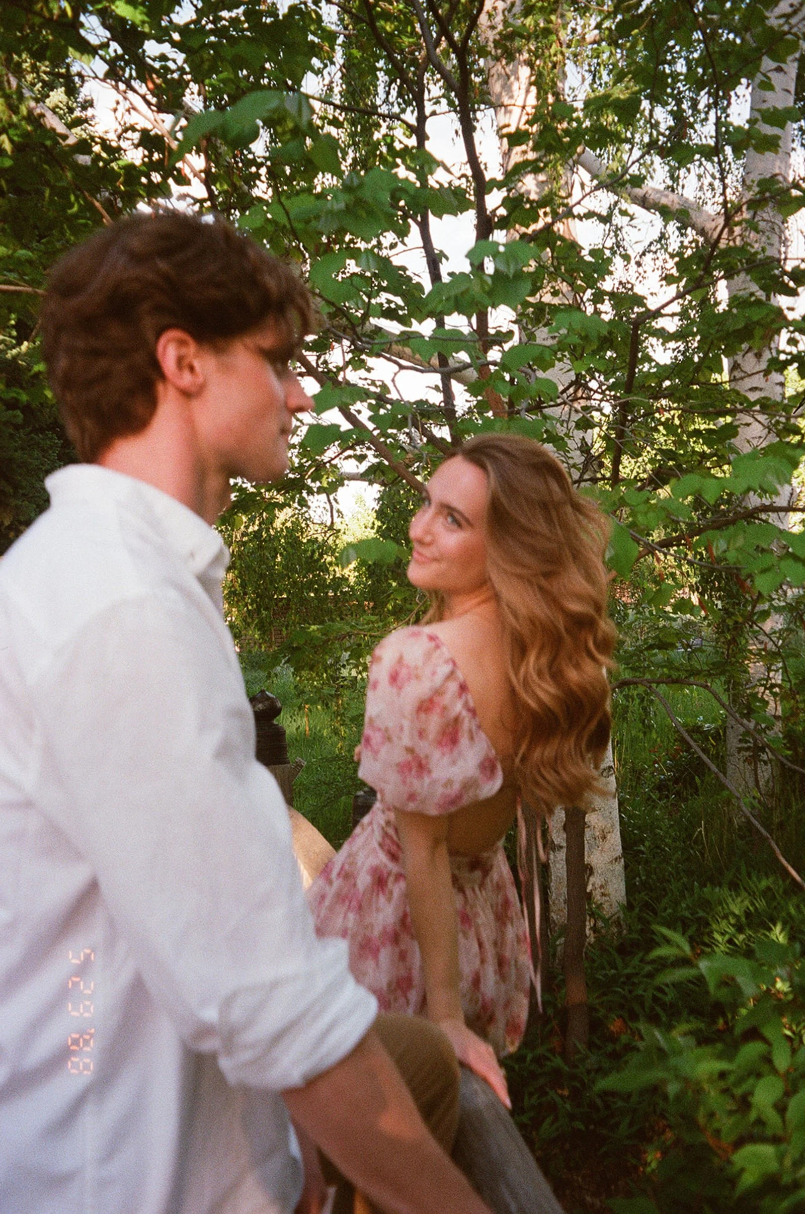 a film engagement photo of a woman looking back at a man in the garden