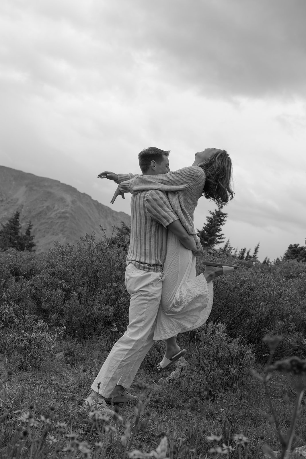 a man holding up a woman during Colorado engagement photos in the mountains