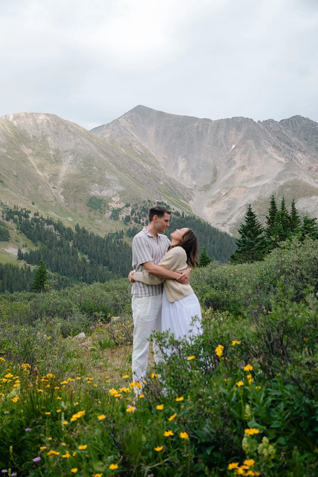 a couple hugging as they stand in a field of wildflowers in a great Engagement Photo Location in CO