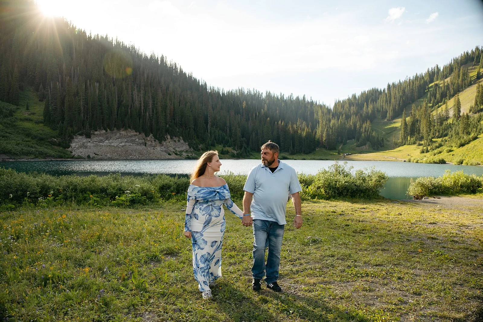 a couple holding hands with a beautiful lake behind them in Colorado