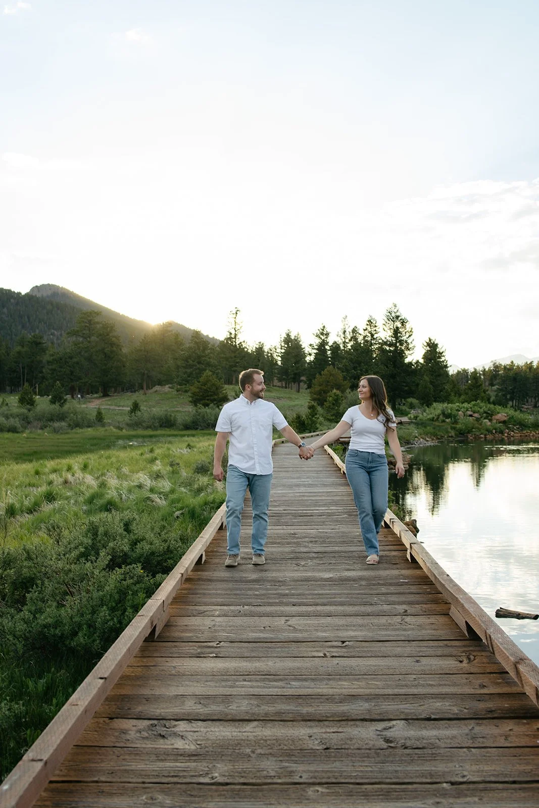 a couple holding hands as they walk on a dock at a beautiful Engagement Photo Location in Colorado 