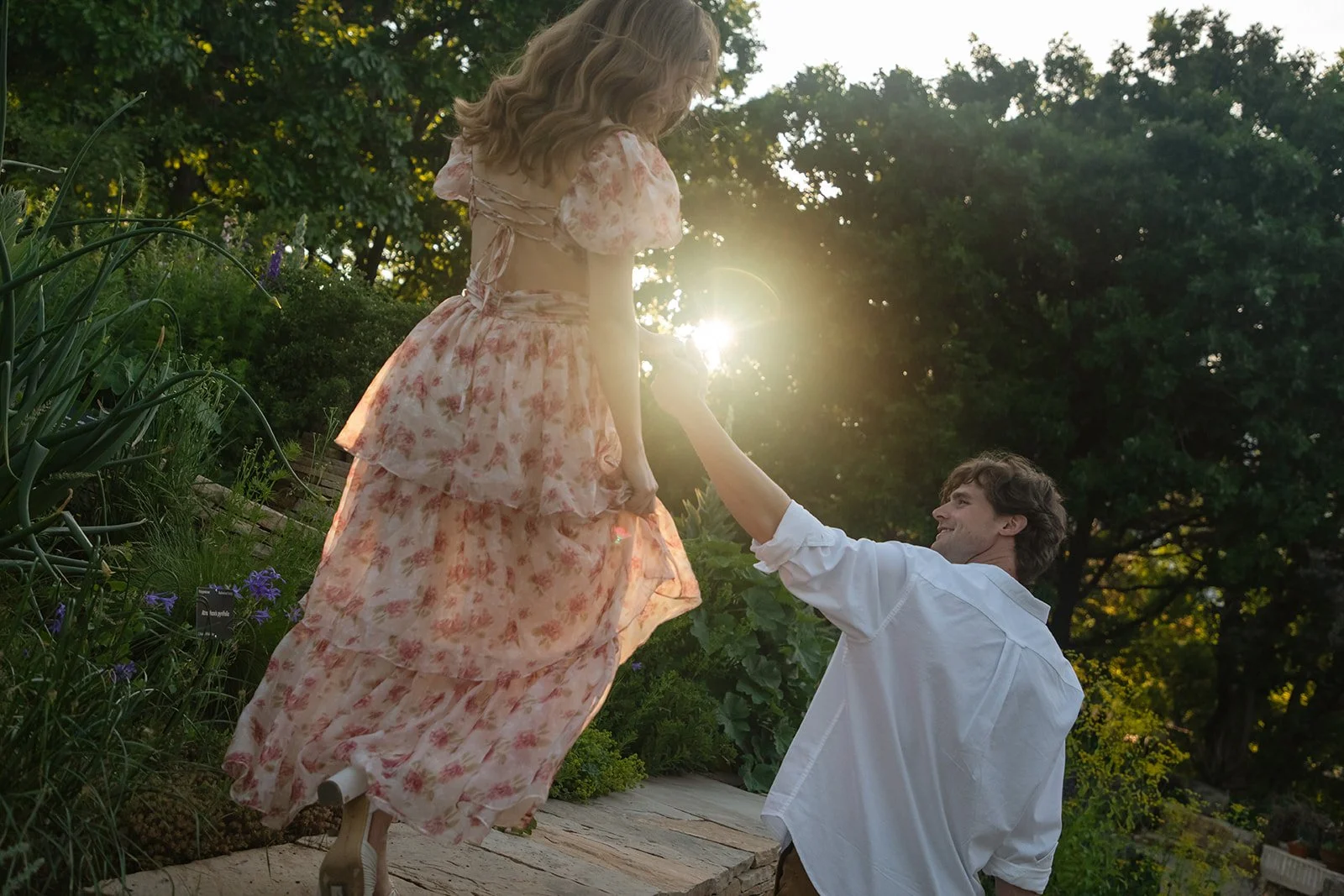 a woman walking on a ledge and holding a man's hand as she goes during engagement photos