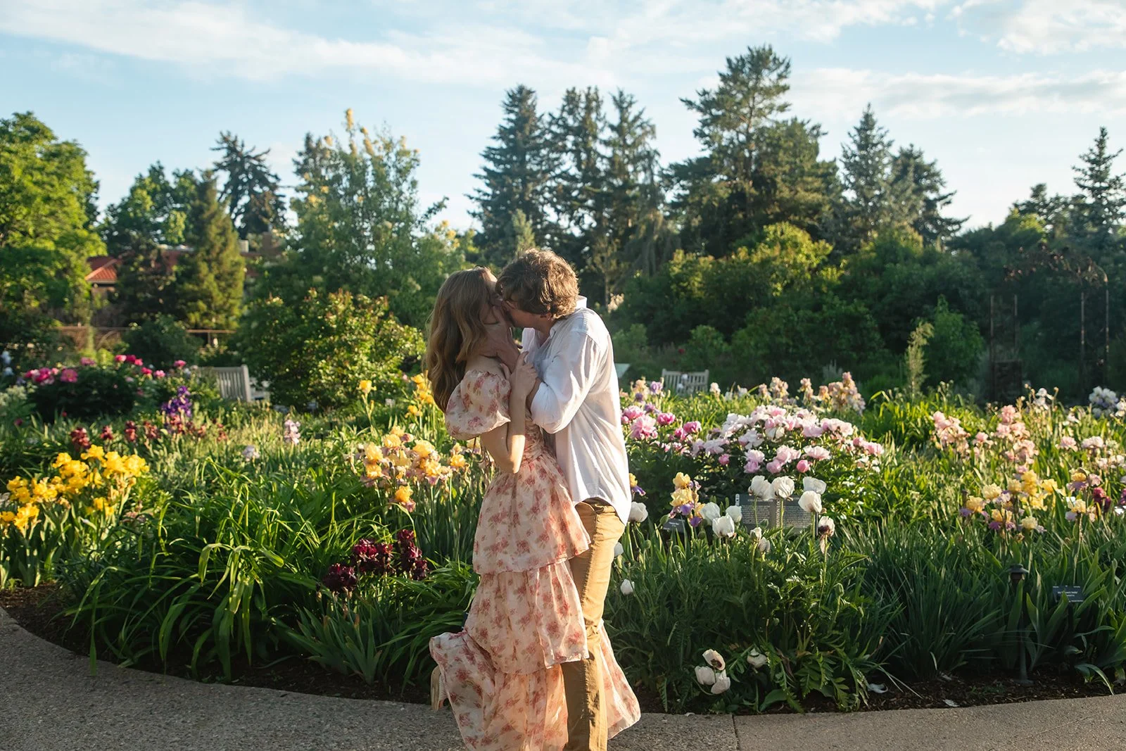 a couple kissing in front of a beautiful garden at a favorite Engagement Photo Location in Denver