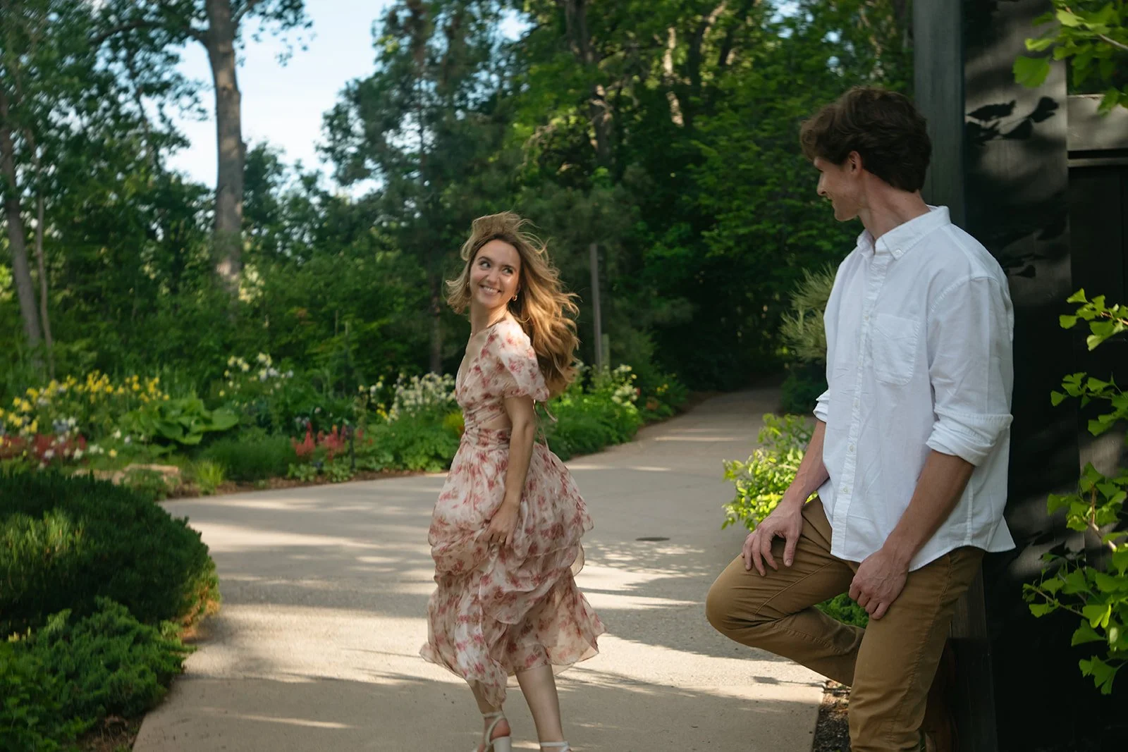 a woman running by a man and him watching her during engagement photos in Denver