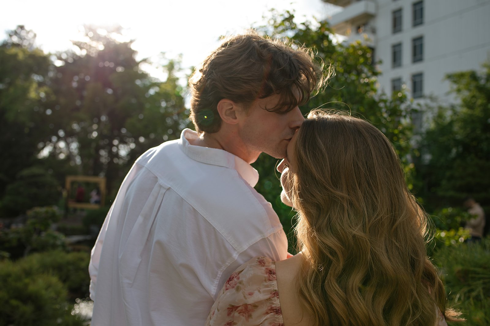 a man kissing a woman's forehead during their engagement photos