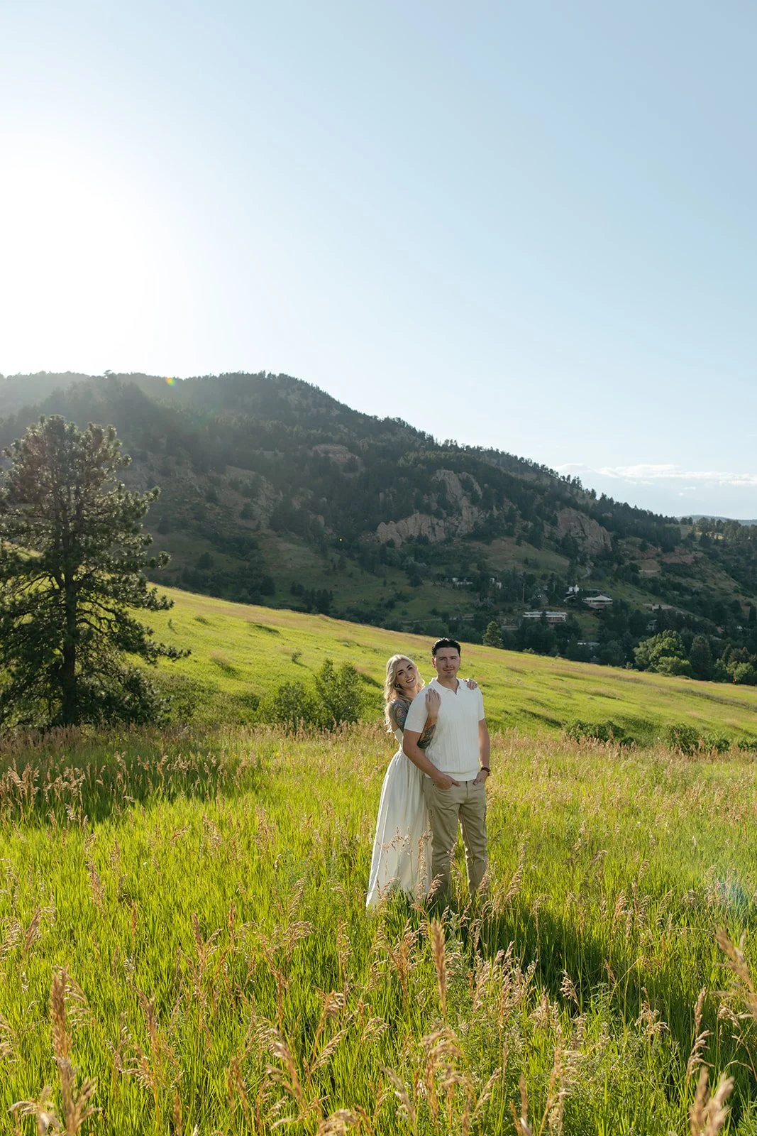 a couple standing in a meadow with beautiful mountain views at a favorite Engagement Photo Location in Colorado