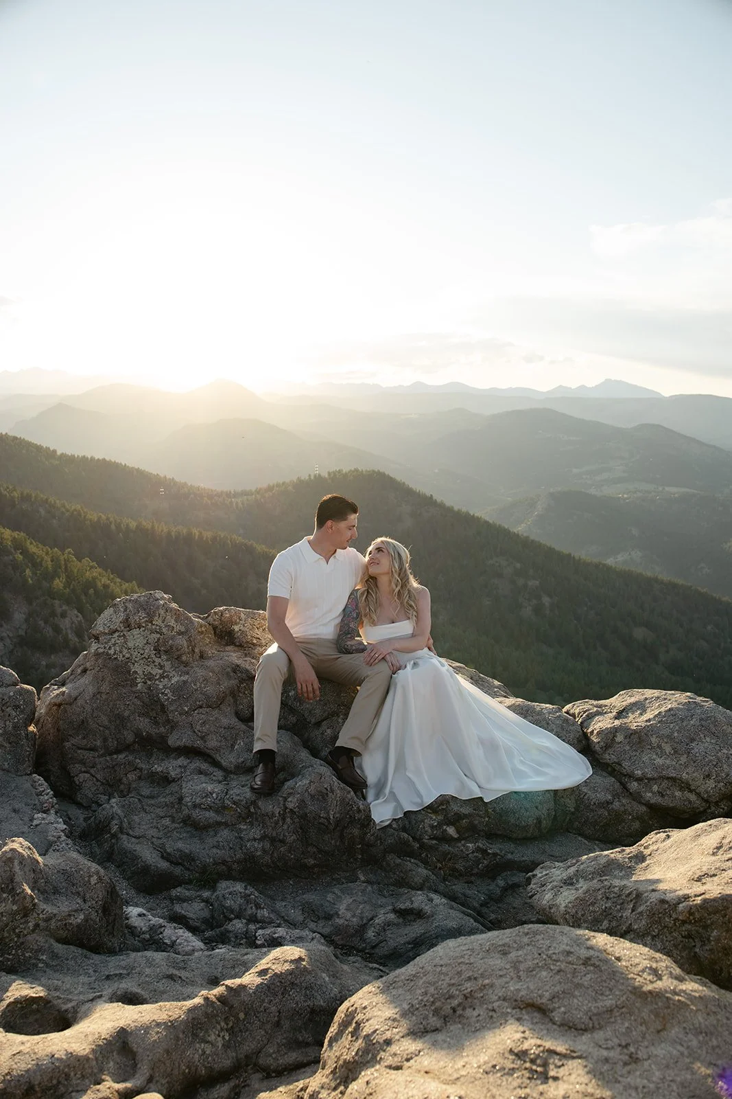 a couple sitting on top of a mountain at one of the best Engagement Photo Locations in Colorado