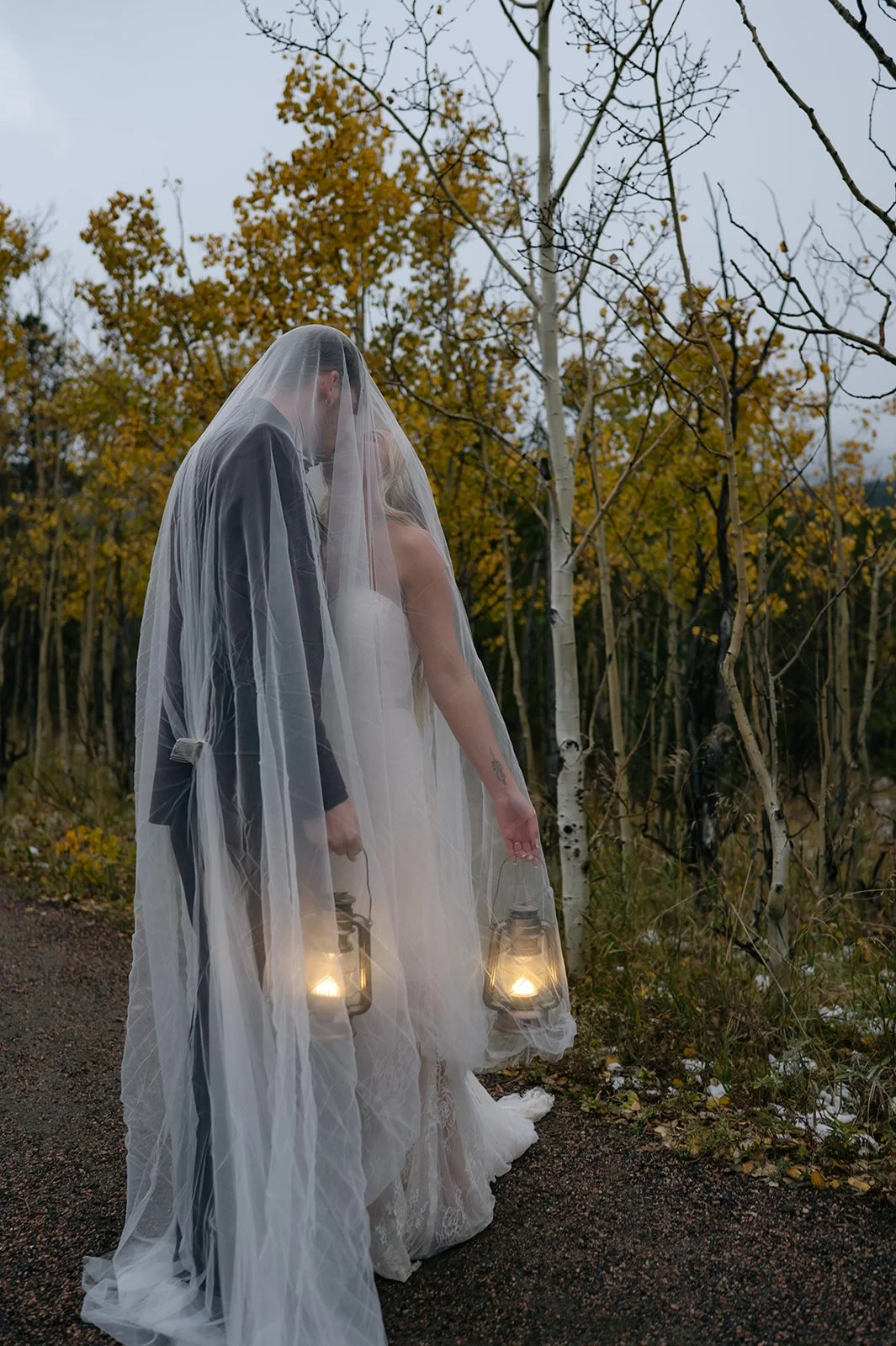 bride and groom portrait underneath a veil as they hold lanterns 