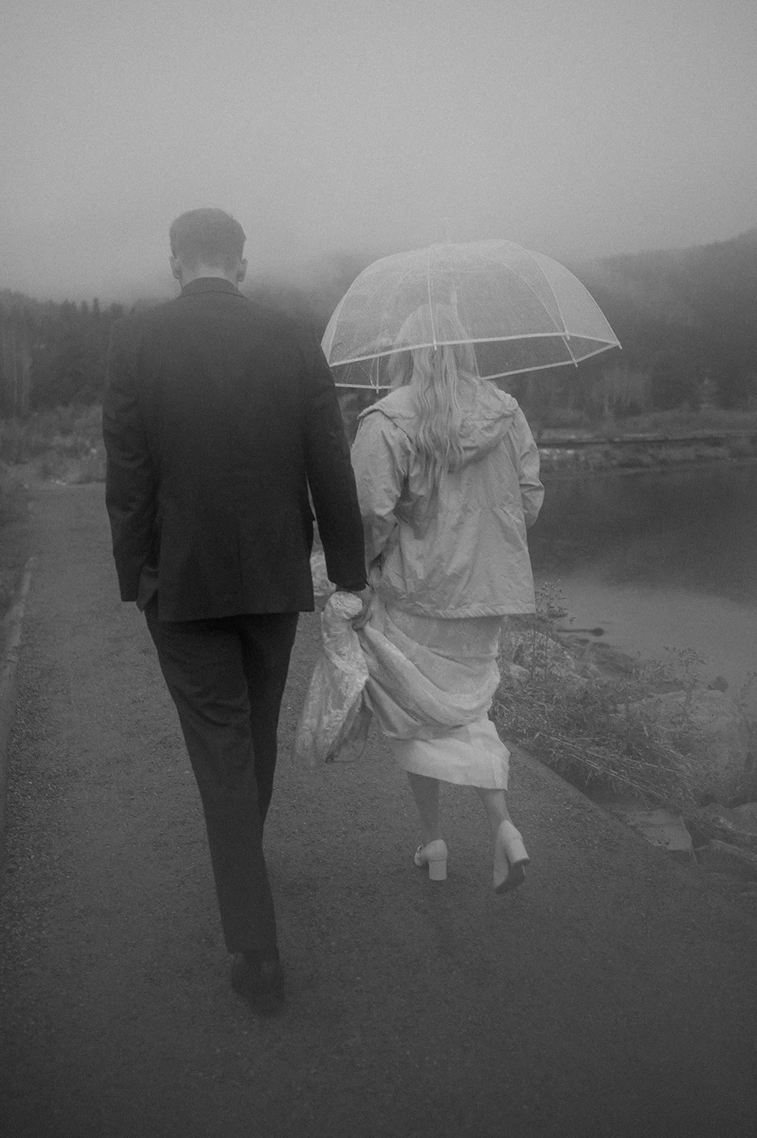 a moody elopement photo of a bride and groom walking in the rain in Colorado