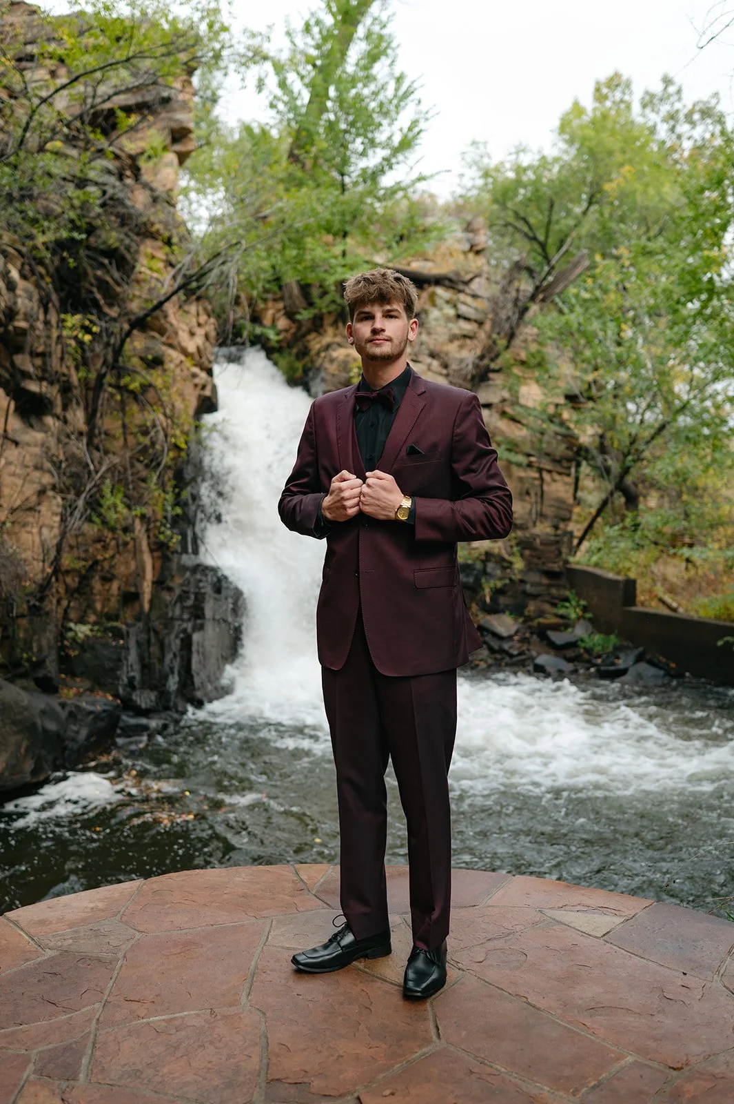 groom portrait in front of a waterfall at a micro wedding venue in CO