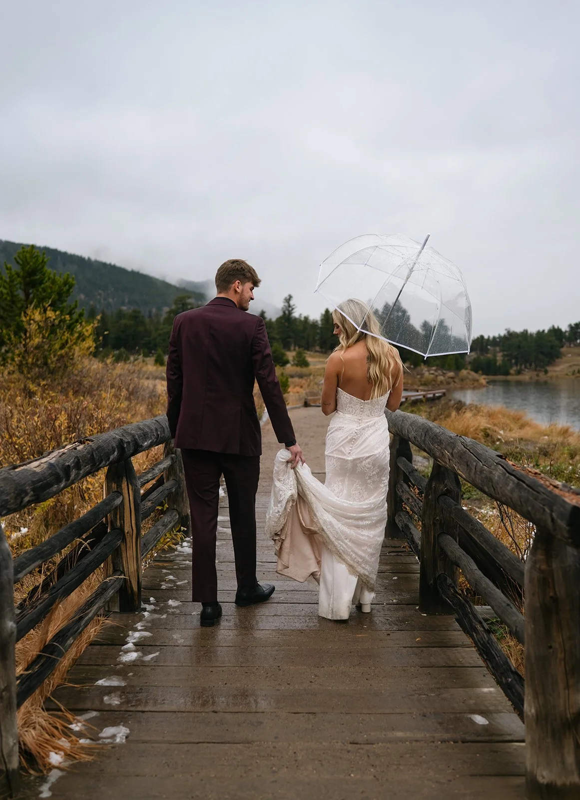 bride and groom walking on a trail as it rains in CO