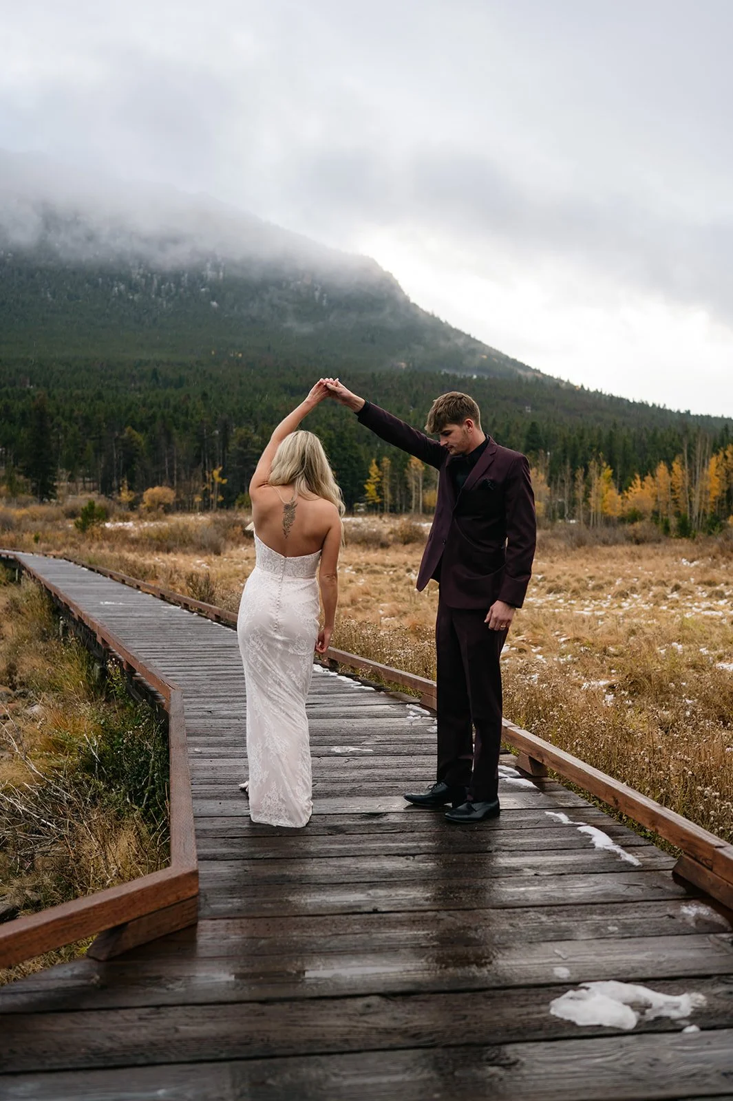 bride and groom dancing on a trail through the mountains