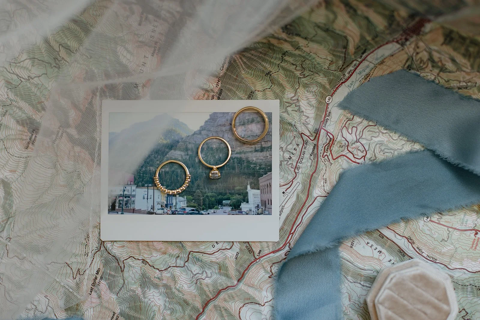 rings laying on a polaroid of the mountains on top of a map or Wedding Detail Photos