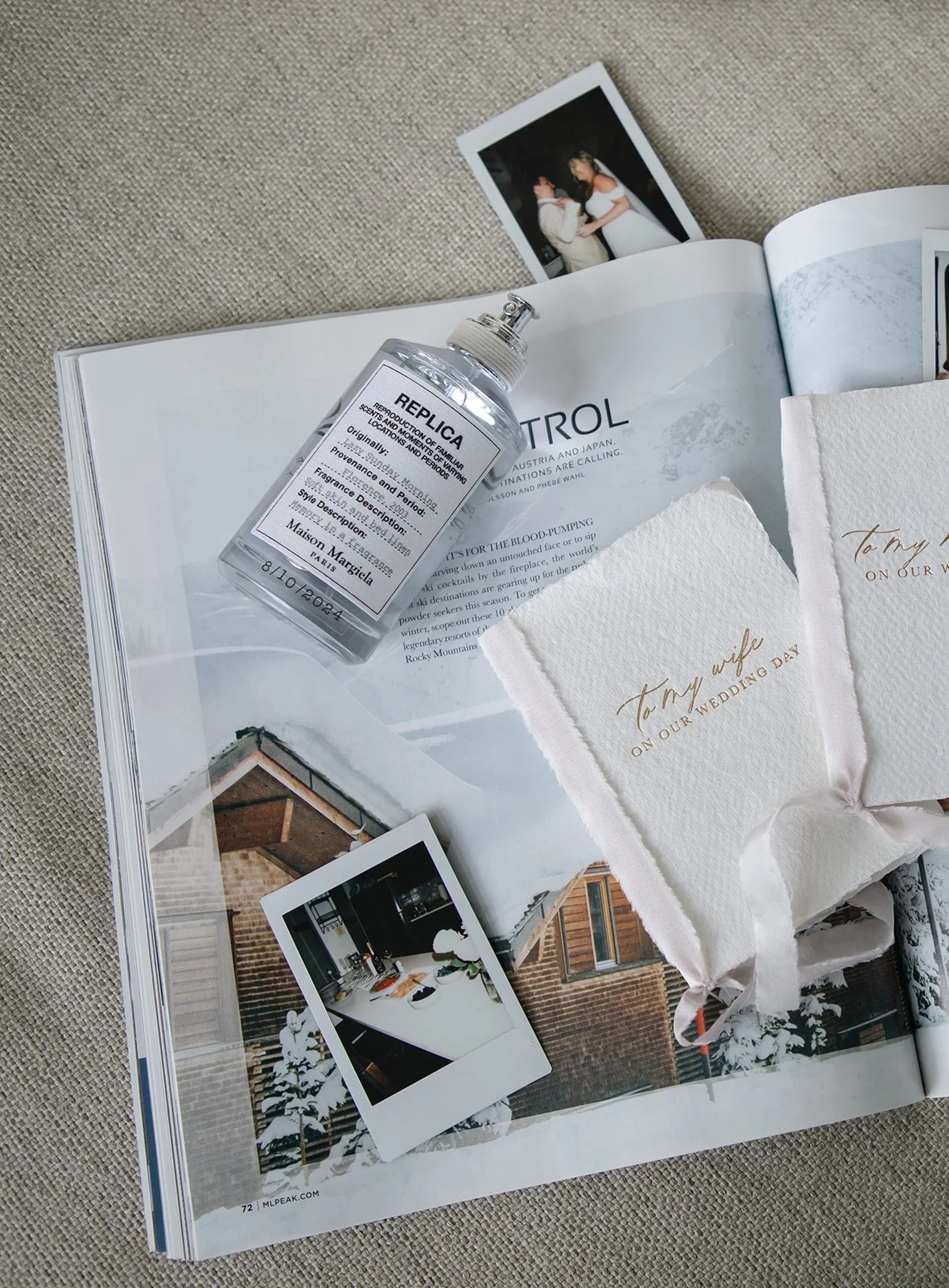 a neutral flatlay with vow books, perfume and images on a book
