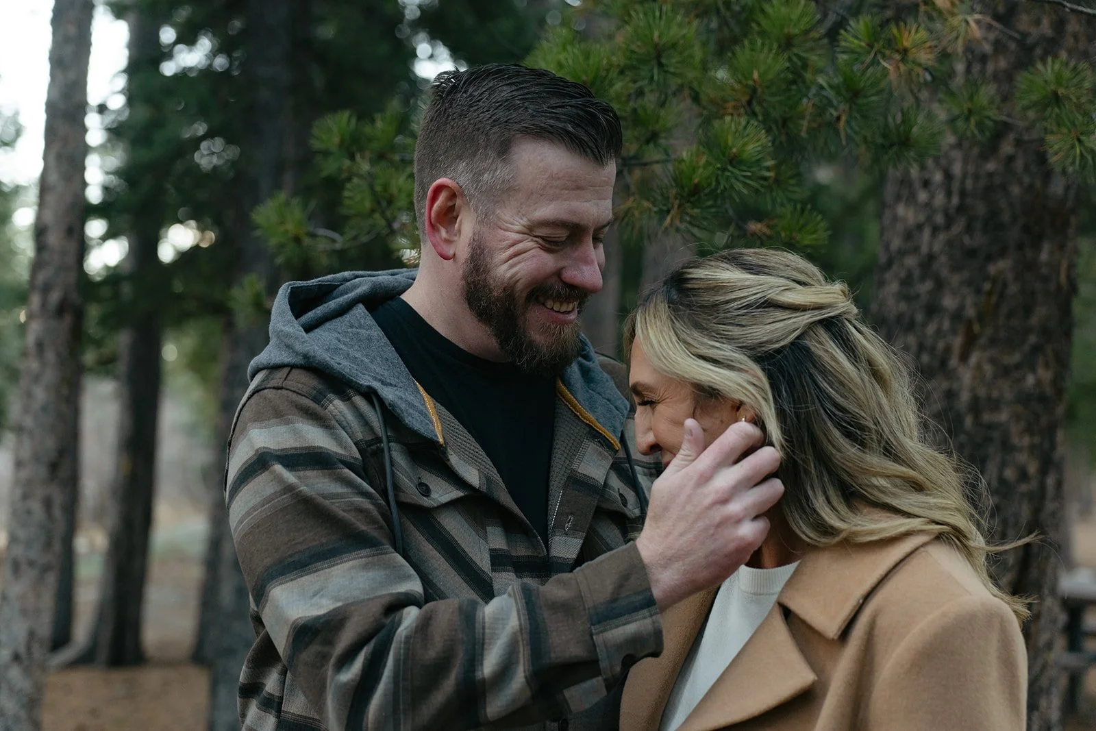 a man brushing back a woman's hair during their engagement photos
