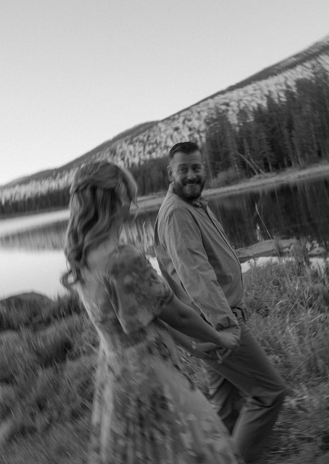 a man looking back at a woman as they hold hands during their engagement photos
