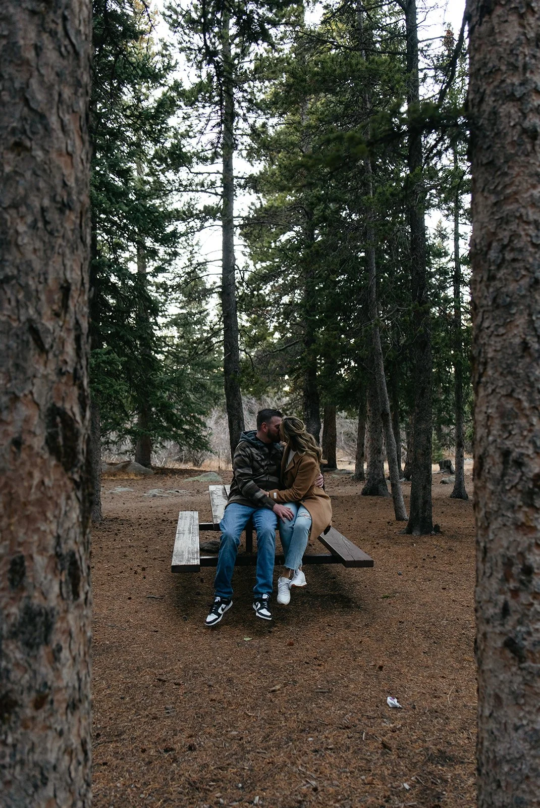 a couple sitting on a picnic table together during their Colorado engagement photos