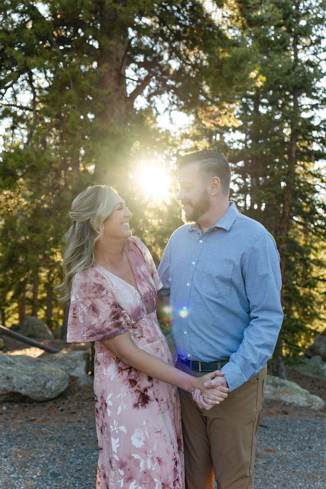 a couple smiling at each other as the sun shines between them 