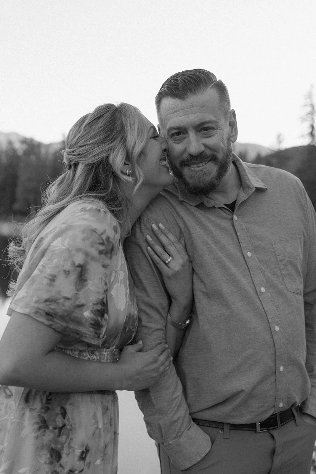 a woman nuzzling into a man during their lake engagement photos in CO