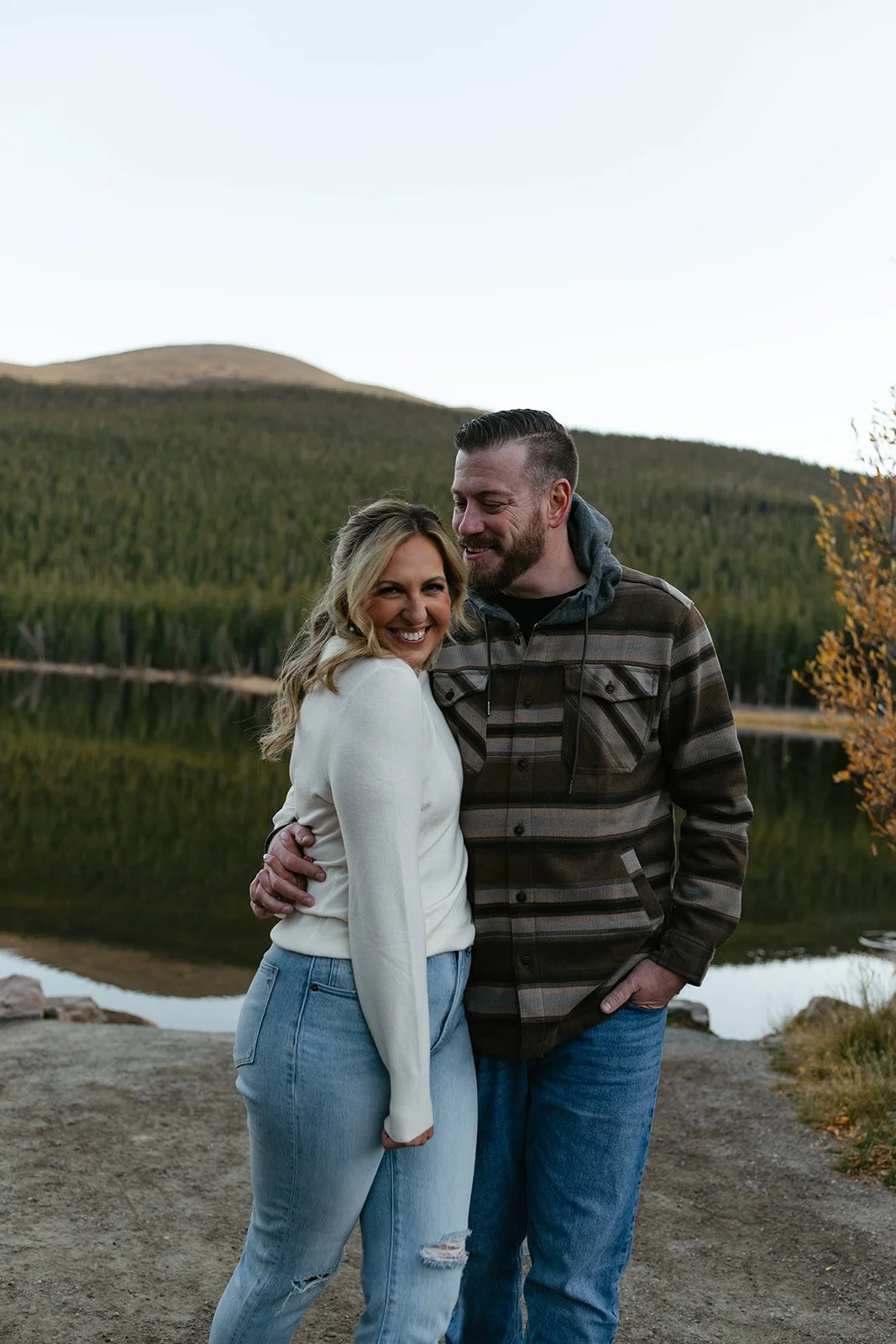 a couple posing in front of a lake 
