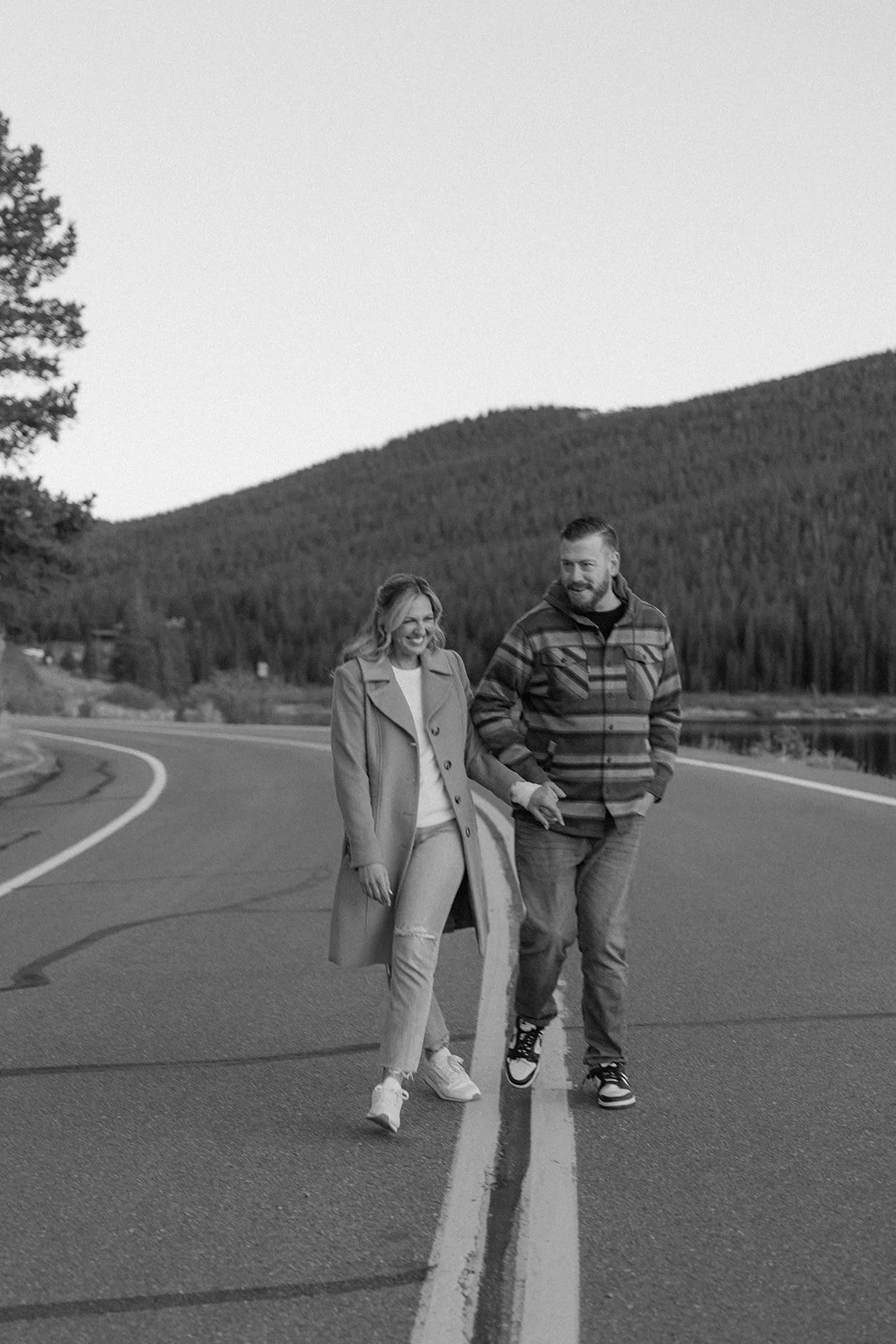 a couple laughing on a road during their lake engagement photos