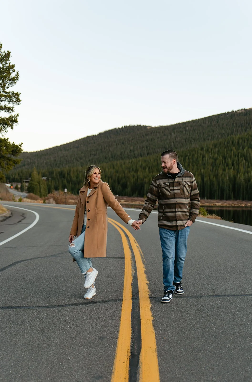 a couple smiling as they walk on a road by echo lake for their engagement photos