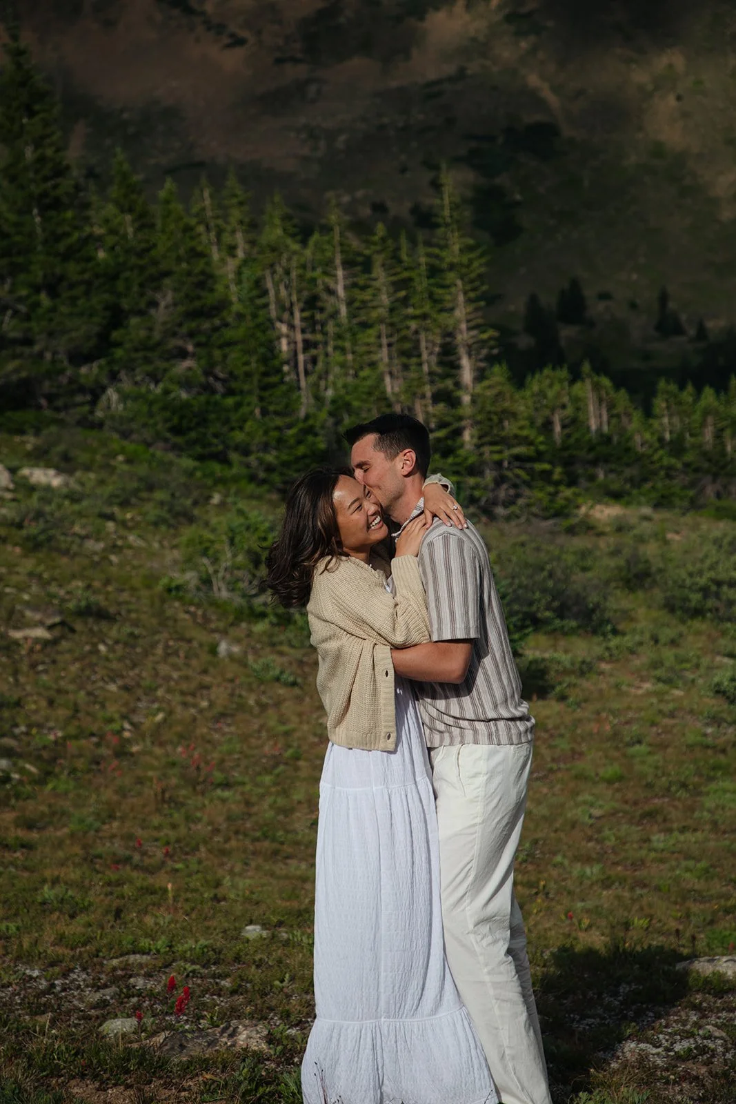 a man kissing a woman as they wear the perfect Colorado Engagement Photo Outfits