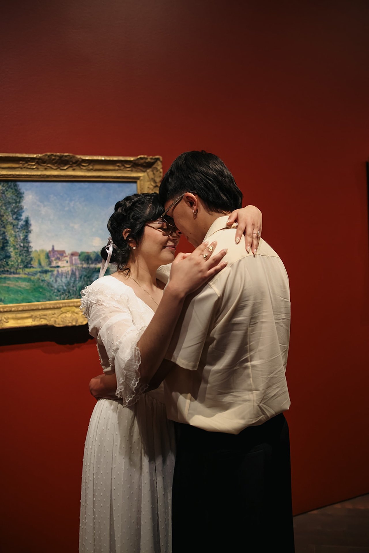 A romantic close-up of a couple slow dancing beneath framed paintings in a museum, capturing the intimacy and elegance of city engagement photos indoors.